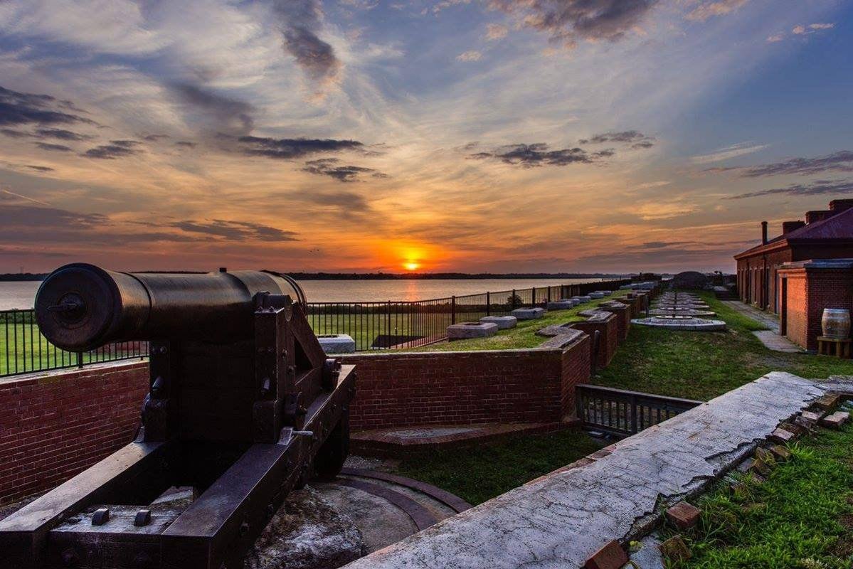 A scenic view from the top of historic Fort Delaware featuring a cannon looking west at a picturesque sunset over the Delaware River.