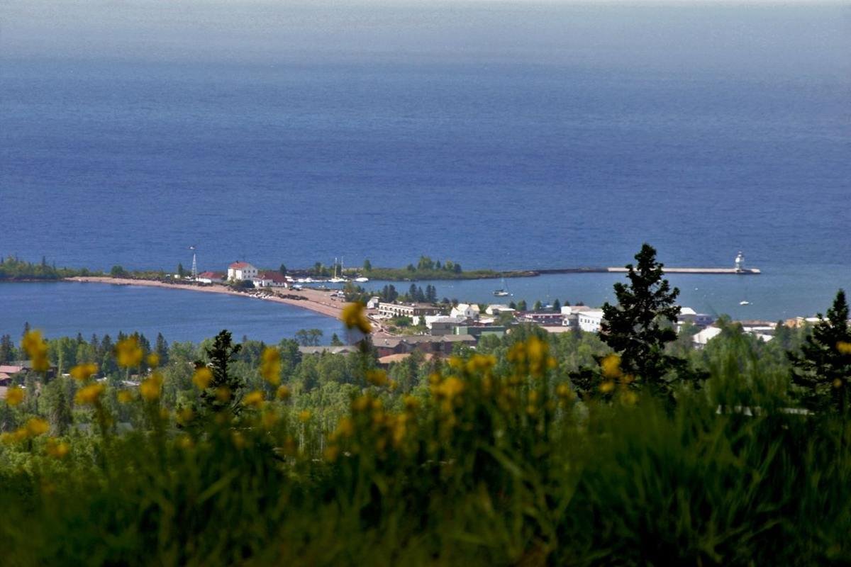 The small town of Grand Marais (population 1100) lies 1000 feet below this overlook perched on a steep hillside. The natural and man-made breakwaters and two lighthouses of Grand Marais gracefully embrace the entrance to the harbor. The deep blue of Lake Superior makes up the background.