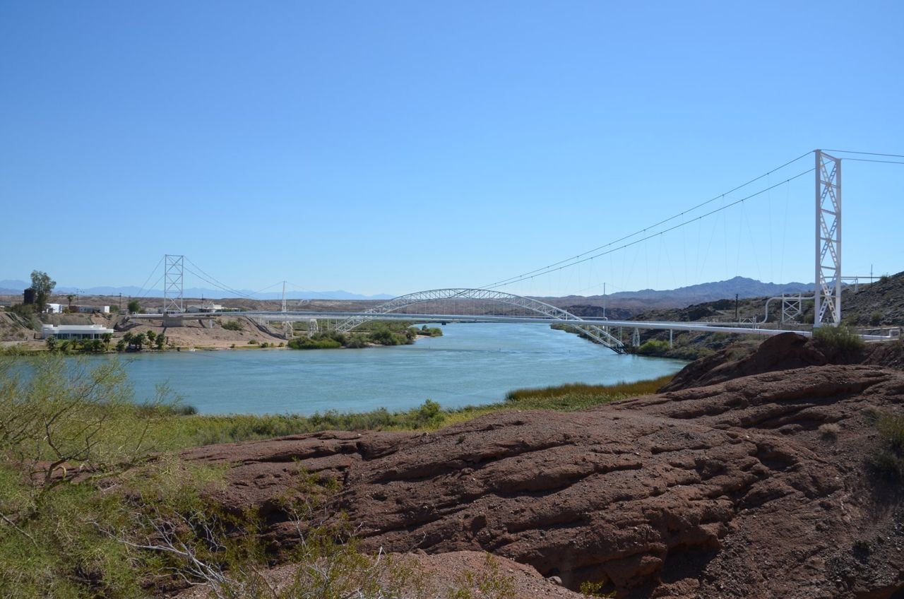 From a rocky knoll, the Colorado River gently flows downstream with the magnificent Trails Arch Bridge in the background. The River forms the natural boundary separating Arizona and California. Once on the
California side, Route 66 travelers could rest and prepare themselves for an incredible and dangerous journey. Looking forward a once-in-a-lifetime adventure on Route 66 across the desolate but beautiful Mojave Desert.
Looking back, the graceful, refreshing waters of the Colorado River.