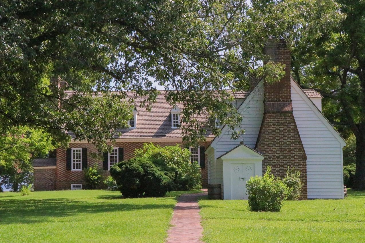 Two buildings surrounded by green foliage with a brick path leading to the buildings.