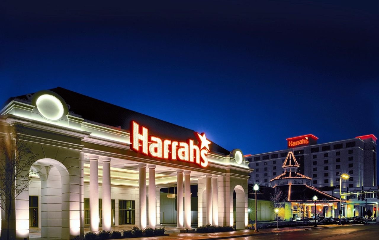 The lights and pillars of Harrah's Hotel and Riverboat Casino glow brightly against the blue night sky.