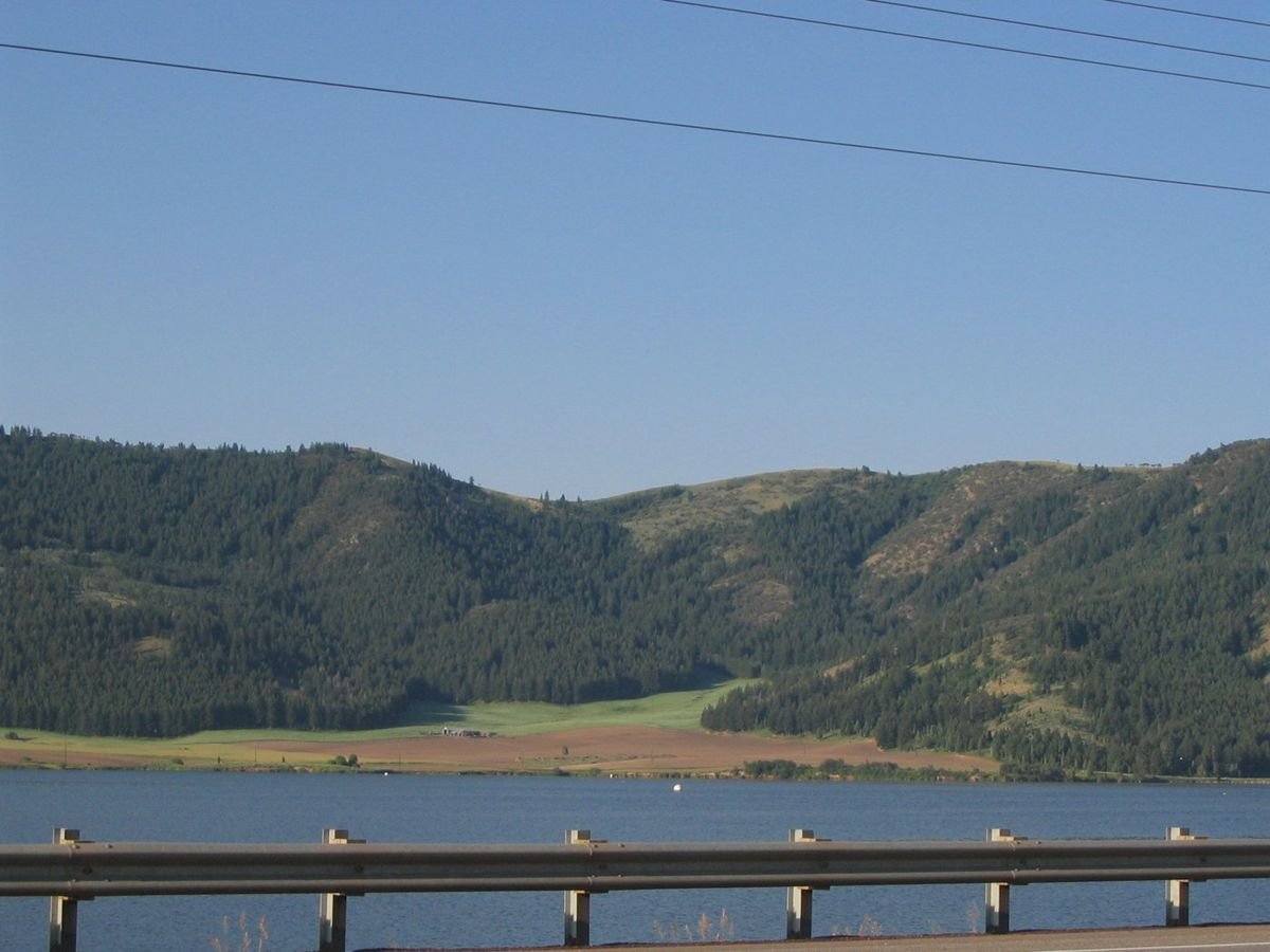 A railing beside the highway seems to hold in the water that surrounds the mountain base.
