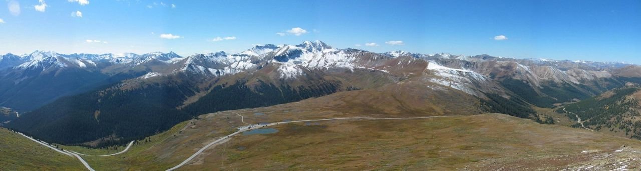 In this panoramic view, Highway 82 crosses the summit of Independence Pass at an elevation of 12,095 feet, one of the highest paved roads in the US. Stretching off to the west from the summit is the Roaring Fork River valley leading to Aspen, and to the east, the South Fork of Lake Creek leading to Twin Lakes and beyond.