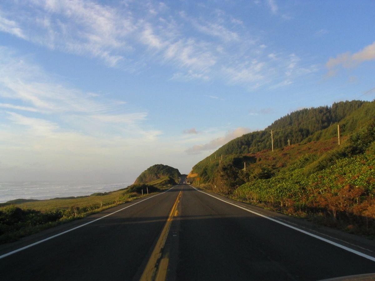 The Pacific Coast Scenic Byway in Oregon combines a drive along the beach with a drive through the forest. The byway is bordered by the Pacific Ocean to the west and pine-covered mountains to the east.