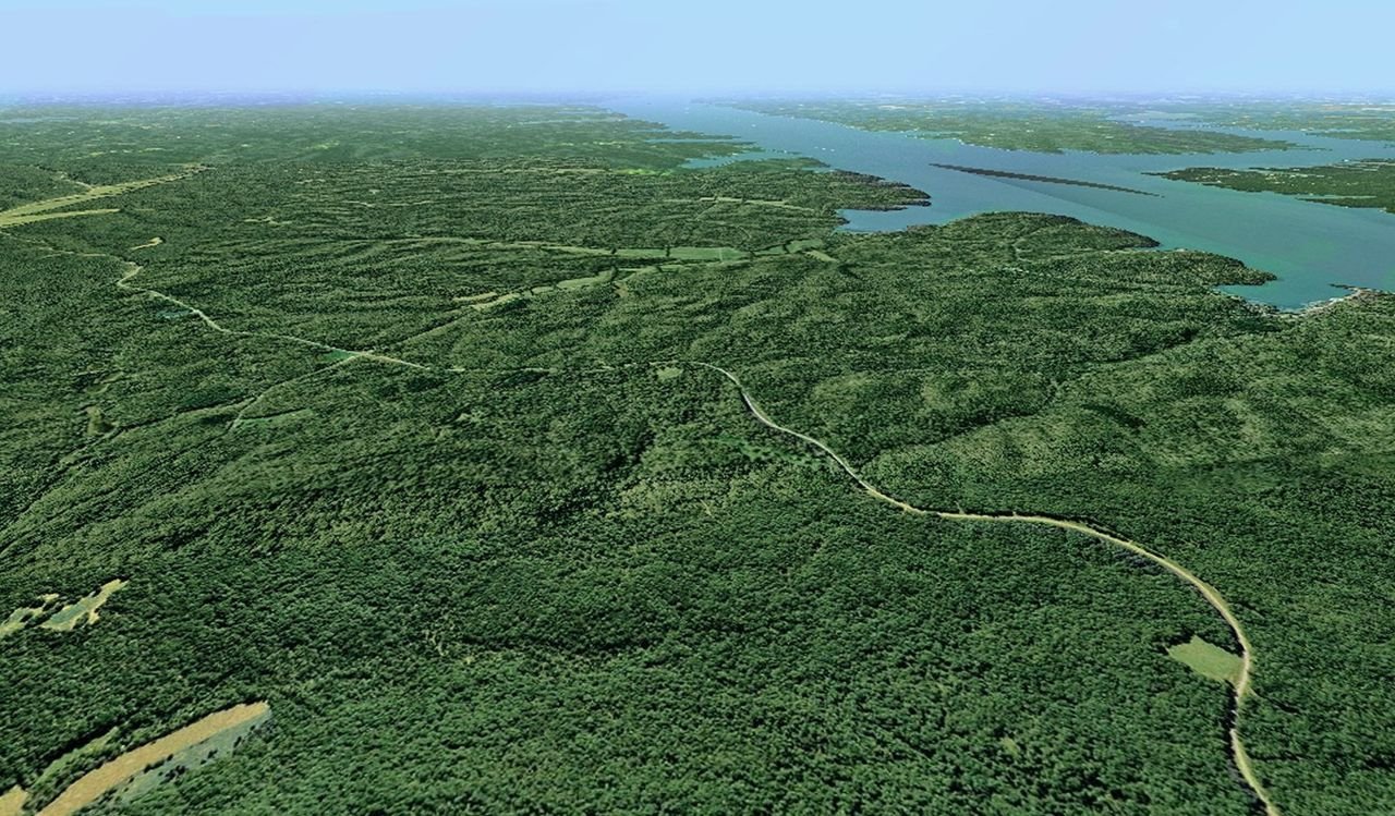 An aerial view of a vast green landscape highlights the Woodlands Trace byway as it winds its way through the forested peninsula called Land Between The Lakes National Recreation Area.