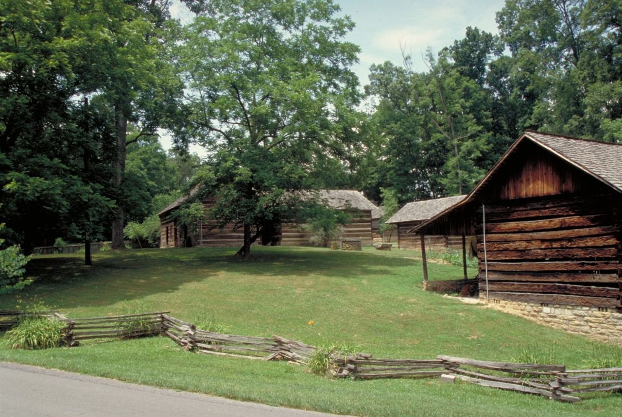 A split rail fence zigzags past log buildings at Levi Jackson State Park.