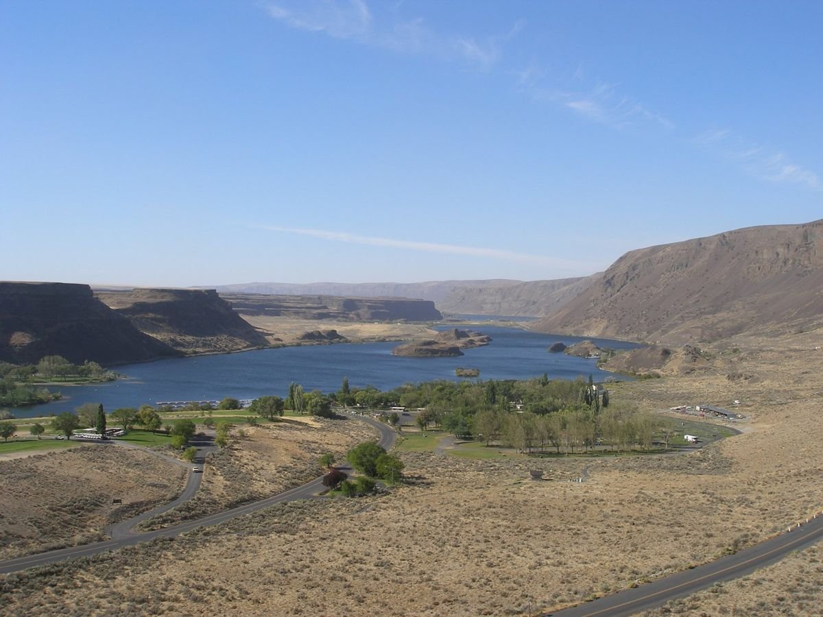 Sun Lakes State Park is bathed in sun, its blue water and tree-lined landscape overlooked by clear skies.