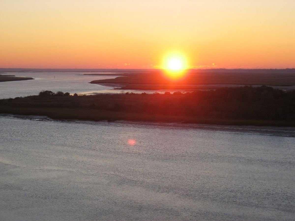 The sun rises casting orange, red, and pink light across the Intracoastal Waterway along the Edisto Island National Scenic Byway.
