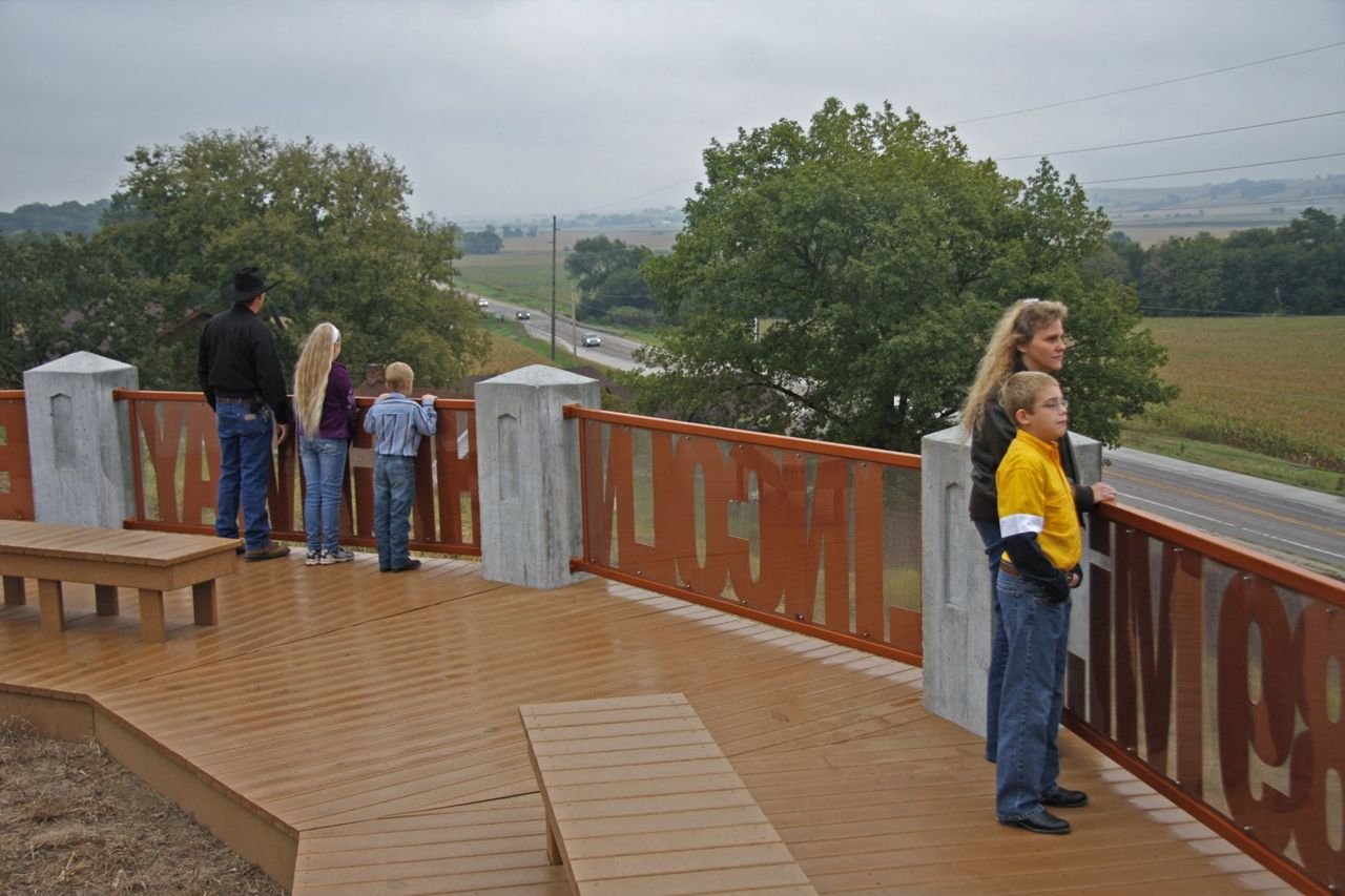 The overlook at the Harrison County Historical Village and Welcome Center’s concrete posts mimic the Boy Scout of America concrete markers and support the 5 metal railings with cutouts with the words “13 States”, “3389 Mi.”, “Lincoln”, “Highway”, “Est. 1913” making this a wonderful opportunity for a family of 5 to see the expansive views of the Boyer River Valley, the Lincoln Highway, and row crops as they disappear into the Loess Hills off into the horizon.